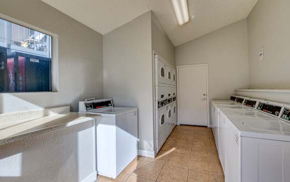 a laundry room with washes and dryers and a window at Summers Point Apartments, Glendale
