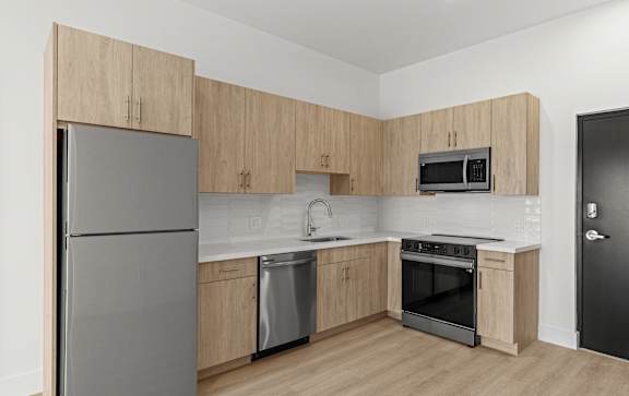 A kitchen with wooden cabinets and a black door.