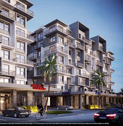 A modern apartment complex with cars parked in front and a cyclist on the street.