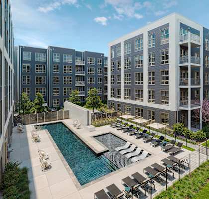 A modern apartment complex with a pool and lounge chairs.