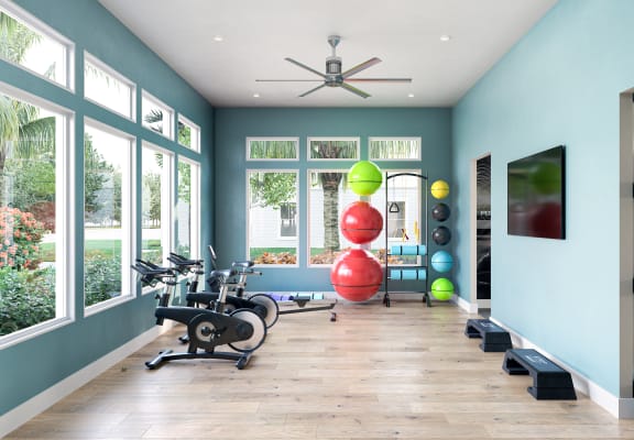 a home gym with ample windows and hardwood flooring