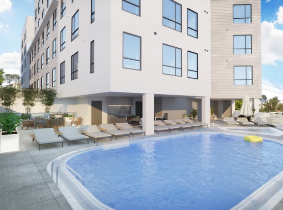 a large swimming pool in front of a white building with a pool