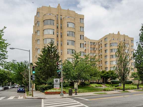 A large beige building with a green traffic light in front of it.