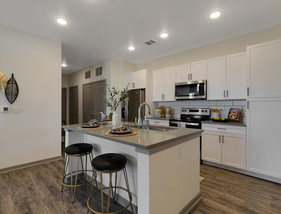 A kitchen with a white counter and bar stools.