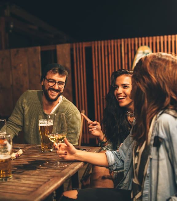 A group of people are gathered around a table, enjoying drinks together.