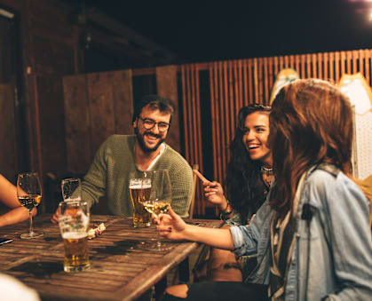 A group of people are gathered around a table, enjoying drinks together.