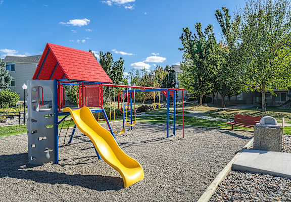 A playground with a red roof and a yellow slide.