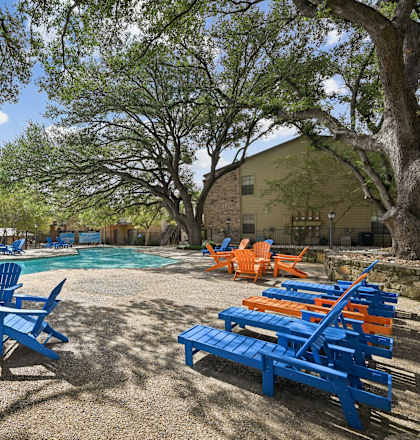 A pool surrounded by blue chairs and tables.