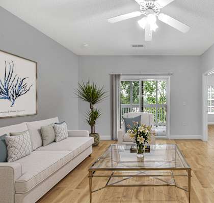 A living room with a white couch, a glass coffee table, and a painting on the wall.