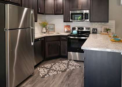 a kitchen with dark wood cabinets and white countertops