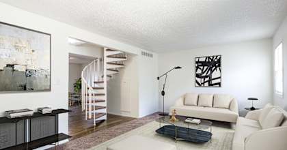 A living room with a white couch, a black coffee table, and a spiral staircase at Spring Creek Townhomes, Illinois, 62702