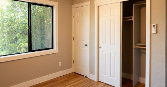 an empty bedroom with hardwood floors and a large window
