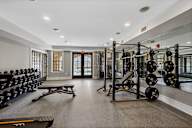 A fitness center with free weights, weight equipment, a window, large mirrors, and double doors leading to a resort-style swimming pool.