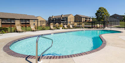 Outdoor swimming pool at Cedar Crest Apartments with lounge chairs and landscaped surroundings for residents to relax.