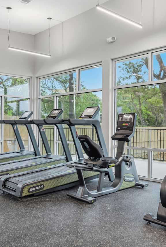 A gym with people exercising and a ceiling fan.