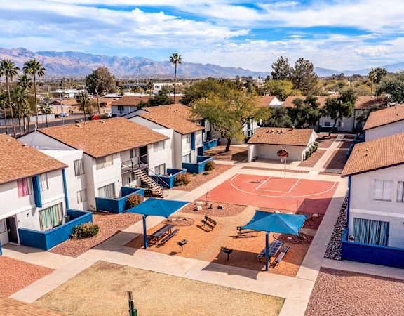 A basketball court is surrounded by houses in a residential area.