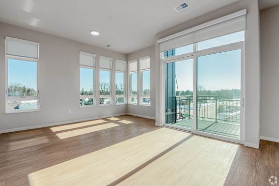 A spacious room with wooden floors and large windows.