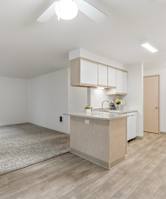 A kitchen area with a sink, stove, and cabinets.