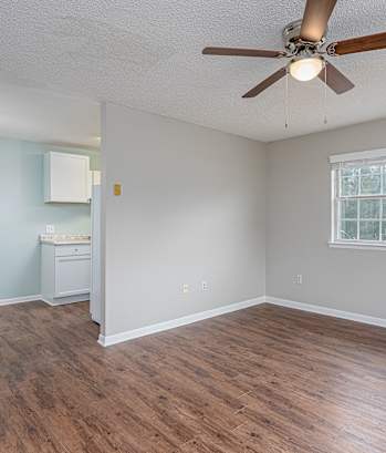 an empty living room with a ceiling fan and a window