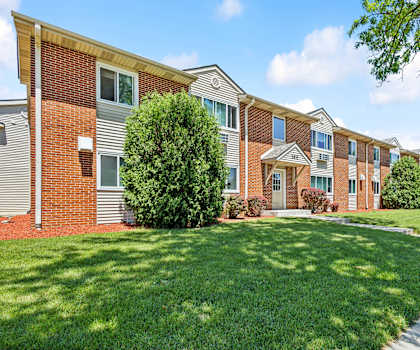 a row of brick apartment buildings with green grass and trees