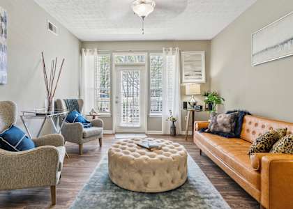 A living room with a couch, chair, and ottoman.
