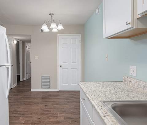 an empty kitchen with white appliances and a door to a hallway