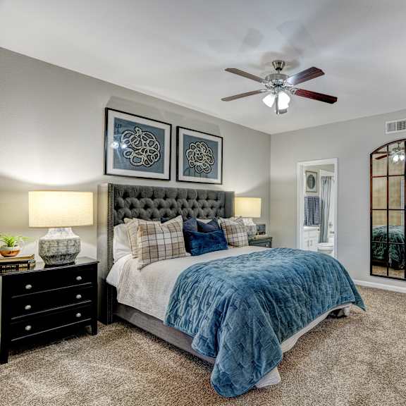 A bedroom with a bed, two lamps, and a chair.at Villages of Briar Forest, Houston, 77077