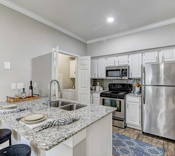 A kitchen with a black granite countertop and white cabinets.at Villages of Briar Forest, Houston, 77077