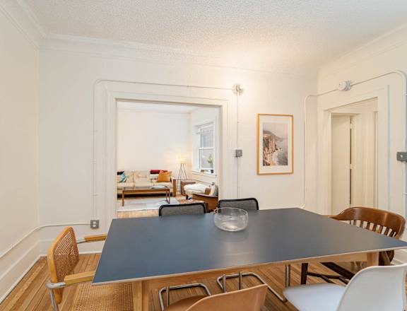 a dining room with a blue table and chairs and a door to a living room