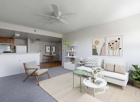 A living room with a white couch, a chair, a coffee table, and a ceiling fan.
