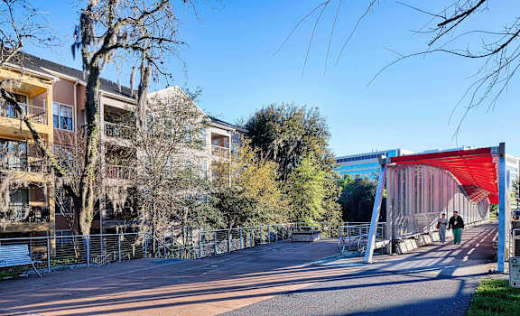 A bridge with a red canopy is in the middle of a street with people walking on it.