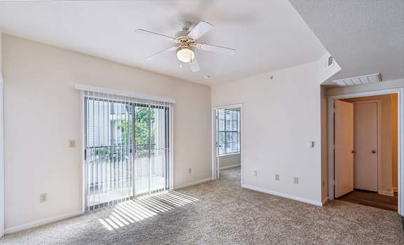 an empty living room with a ceiling fan and a door to a balcony at St. Augustine Estate, Dallas