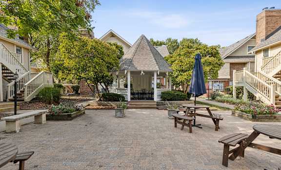 a patio with benches and tables and a gazebo