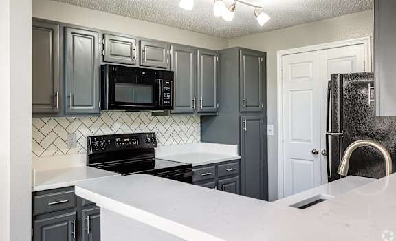 A kitchen with black cabinets and a white counter.