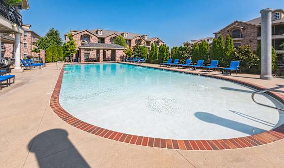 our resort style swimming pool is surrounded by blue lounge chairs and our apartments in the