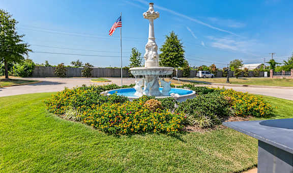 a fountain in the center of a park with an flag
