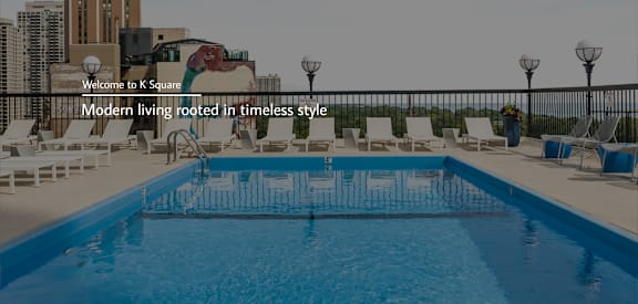 A pool surrounded by chairs and a sign that says "Welcome to K Square".