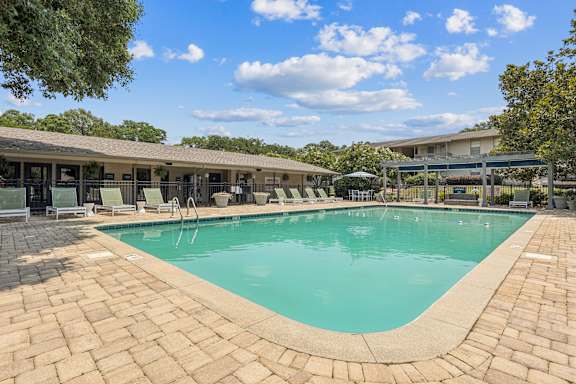 A large outdoor swimming pool surrounded by a brick patio.