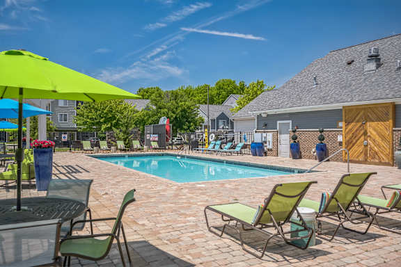 A pool area with chairs and umbrellas on a sunny day.