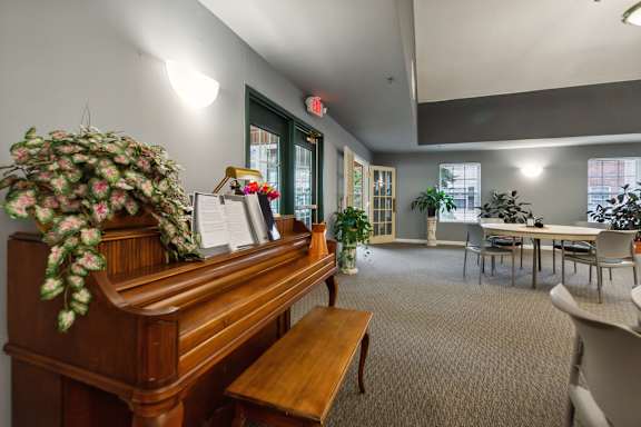 A room with a piano, chairs, and a table.