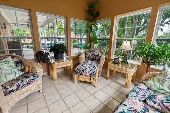 A sunroom with wicker furniture and plants.
