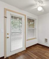 A room with a door, window, and a ceiling fan.