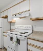 A white stove with a towel on it in a kitchen.
