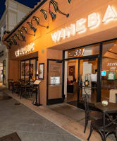 a night view of a wine bar with tables and chairs outside of it