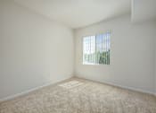 Thumbnail 18 of 20 - A room with a carpeted floor and a window with blinds.