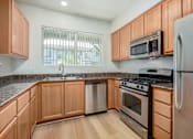 Thumbnail 11 of 20 - A kitchen with wooden cabinets and stainless steel appliances.