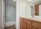 Thumbnail 16 of 20 - A bathroom with a wooden vanity and a white bathtub.
