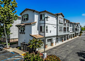 Thumbnail 10 of 20 - A row of modern townhouses with a clear blue sky above.
