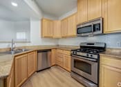 Thumbnail 17 of 20 - A kitchen with wooden cabinets and a black stove top oven.