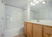 Thumbnail 19 of 20 - A white bathroom with wooden cabinets and a glass shower door.